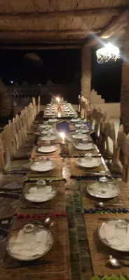 a long table with chairs and plates on it at Auberge Kasbah Dar Sahara Tours in Mhamid
