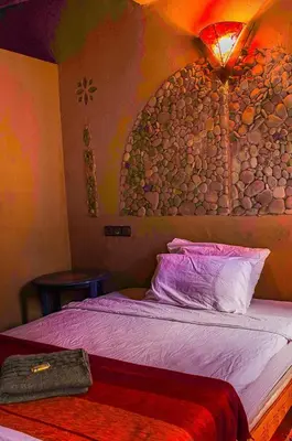 a bedroom with a bed with a rock wall at Auberge Kasbah Dar Sahara Tours in Mhamid