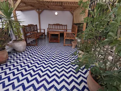 a patio with a table and chairs and potted plants at Dar Ben Daoud avec piscine et terrasse privee in Fès