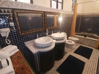 a bathroom with two sinks and a tub and a toilet at Dar Ben Daoud avec piscine et terrasse privee in Fès