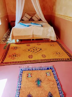 a bedroom with a bed with a rug on the floor at La perle de saghro in Nkob