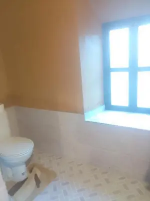 a bathroom with a toilet and a window at La perle de saghro in Nkob