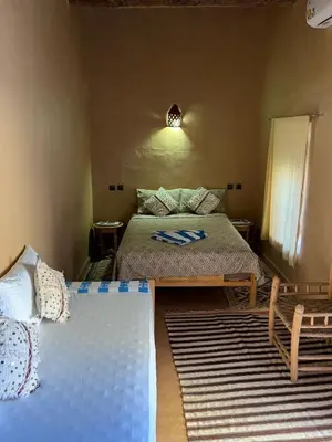 a bedroom with two twin beds and a table at La perle de saghro in Nkob