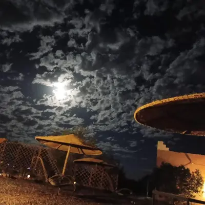 a cloudy sky with the moon and an umbrella at LESCALE DE OUARZAZATE in Ouarzazate