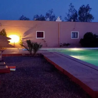 a swimming pool in front of a building at night at LESCALE DE OUARZAZATE in Ouarzazate