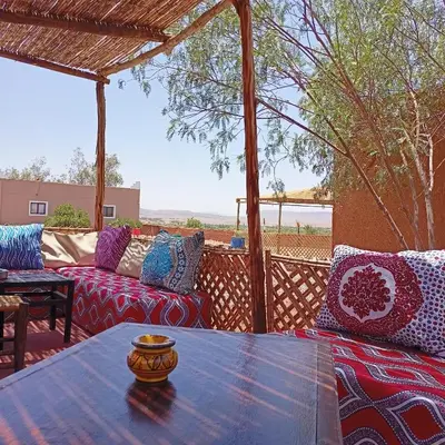 a patio with a table and couches on a deck at LESCALE DE OUARZAZATE in Ouarzazate