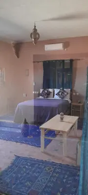 a bedroom with a bed and a table in it at LESCALE DE OUARZAZATE in Ouarzazate
