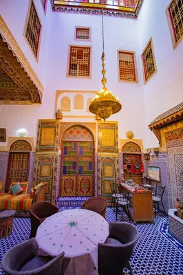 a room with a table and chairs and a chandelier at Riad Fes Hayat - Confort Stay in Fès