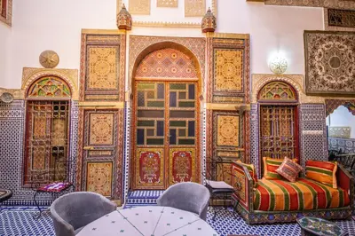 a room with a large wooden door with a couch and chairs at Riad Fes Hayat - Confort Stay in Fès