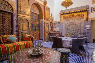 a living room with a table and chairs in a room with colorful tiles at Riad Fes Hayat - Confort Stay in Fès