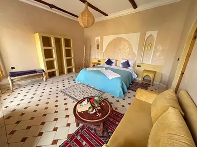 a bedroom with a bed and a couch and a table at Oasis Tilogui-Luxury Hotel Restaurant and Desert Excursions In Zagora in Zagora
