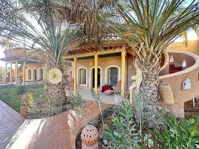 a house with two palm trees in front of it at Oasis Tilogui-Luxury Hotel Restaurant and Desert Excursions In Zagora in Zagora