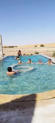 a group of people in a swimming pool on the beach at Takojt in Merzouga