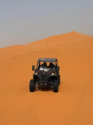 two people in a jeep driving through a desert at Takojt in Merzouga