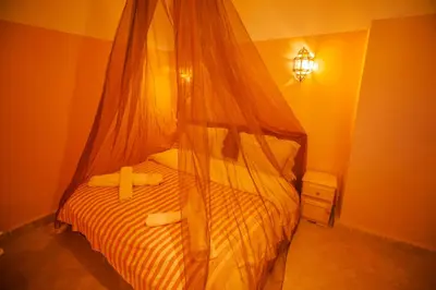 a bedroom with a bed with a mosquito net at Takojt in Merzouga