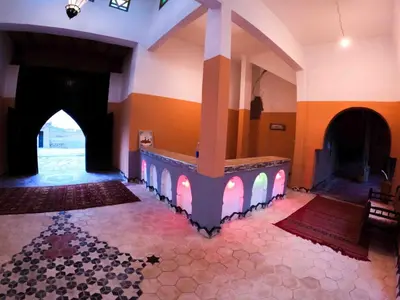 a room with a large fireplace in a building with a floor at Takojt in Merzouga