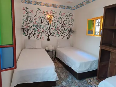 a room with two beds and a wall with a tree mural at Riad Safir Medina Fes in Fès