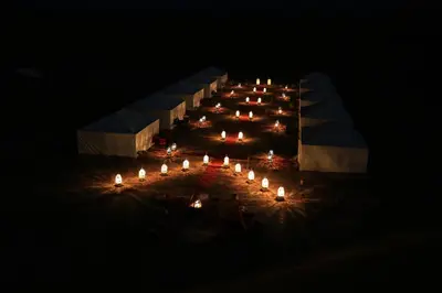 a long table with lit candles in the dark at Luxury Berber Camp in El Gouera