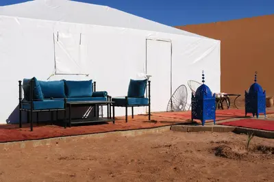 two blue chairs and a table in a tent at Luxury Berber Camp in El Gouera