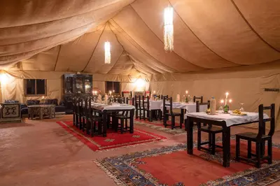 a dining room with tables and chairs in a tent at Luxury Camp Merzouga in Merzouga