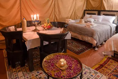 a bedroom with a bed and a table with fruits and candles at Luxury Camp Merzouga in Merzouga