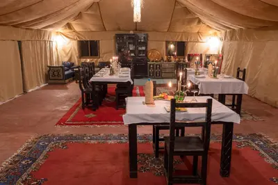 a dining room in a tent with tables and chairs at Luxury Camp Merzouga in Merzouga