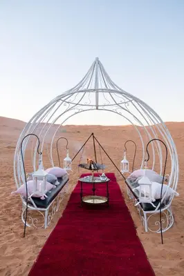 a tent in the desert with two beds and a red carpet at Luxury Camp Merzouga in Merzouga