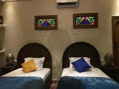 two beds in a bedroom with two stained glass windows at Riad le petit ksar in Meknès