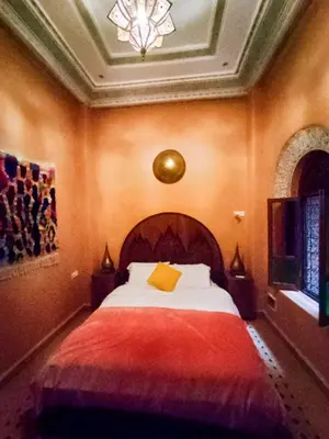 a bedroom with a large bed with a red blanket at Riad le petit ksar in Meknès