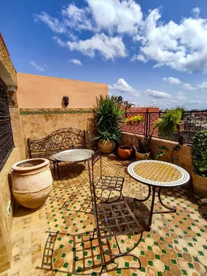 a patio with two tables and a bench at Riad le petit ksar in Meknès