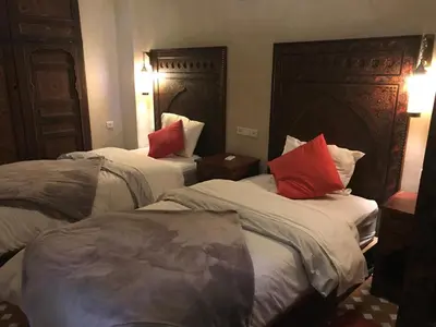 a hotel room with two beds with red pillows at Riad le petit ksar in Meknès
