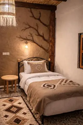 a bedroom with a bed with a tree painting on the wall at Chez aubazine in Merzouga