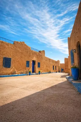 a row of brick buildings on a dirt road at Chez aubazine in Merzouga