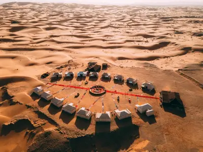 an aerial view of a desert with a group of tents at Desert Luxury Camp Morocco in Merzouga