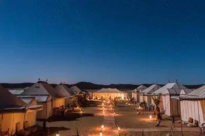 a group of tents in the desert at night at Desert Luxury Camp Morocco in Merzouga