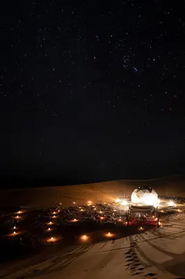 a night scene of a desert with a starry sky at Desert Luxury Camp Morocco in Merzouga