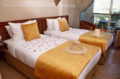 two beds in a hotel room with hats on top of them at Borj Des Cascades & Spa in Ouzoud