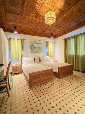 a bedroom with two beds and a chandelier at Desert Villa Boutique Hotel Merzouga in Merzouga