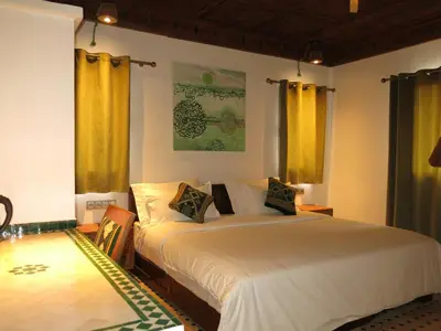 a bedroom with a large white bed with yellow curtains at Desert Villa Boutique Hotel Merzouga in Merzouga