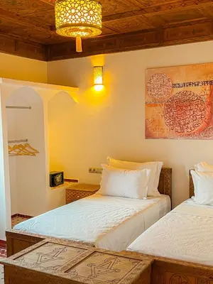 a bedroom with two beds and a painting on the wall at Desert Villa Boutique Hotel Merzouga in Merzouga