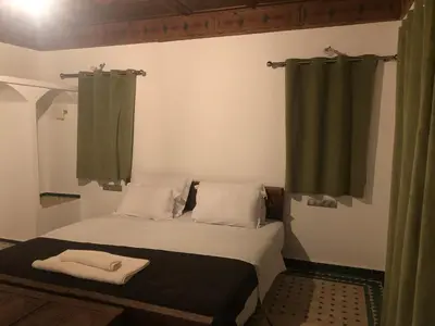 a small bedroom with a bed and green curtains at Desert Villa Boutique Hotel Merzouga in Merzouga