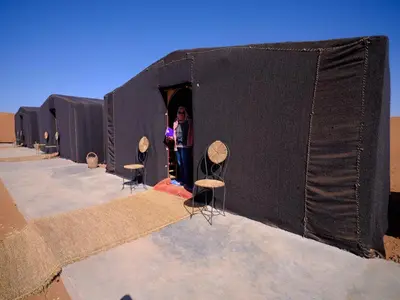 a woman standing in a black tent with stools in it at Chigaga Luxury Camp in Mhamid