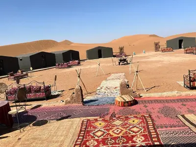 a desert with windmills and a rug in the desert at Chigaga Luxury Camp in Mhamid