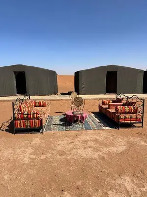 two couches and a table and chairs in the desert at Chigaga Luxury Camp in Mhamid