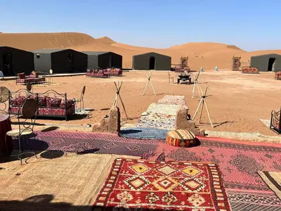 a desert area with tents and a rug in the desert at Chigaga Luxury Camp in Mhamid