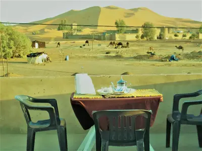 a table and chairs with a view of a desert at Tifinagh Guest House in Merzouga
