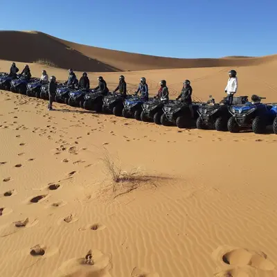 a group of people riding motorcycles in the desert at Tifinagh Guest House in Merzouga