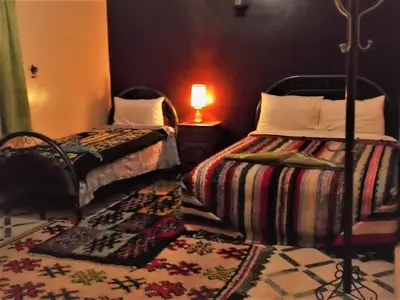 a bedroom with two beds and a lamp and a rug at Tifinagh Guest House in Merzouga