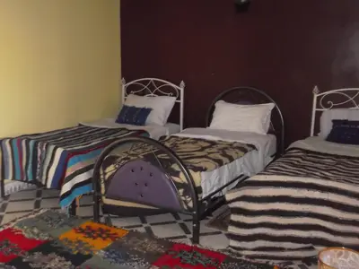a room with two beds and a rug at Tifinagh Guest House in Merzouga