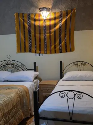 a room with two beds and a hanging flag at Dar Gamra in Merzouga